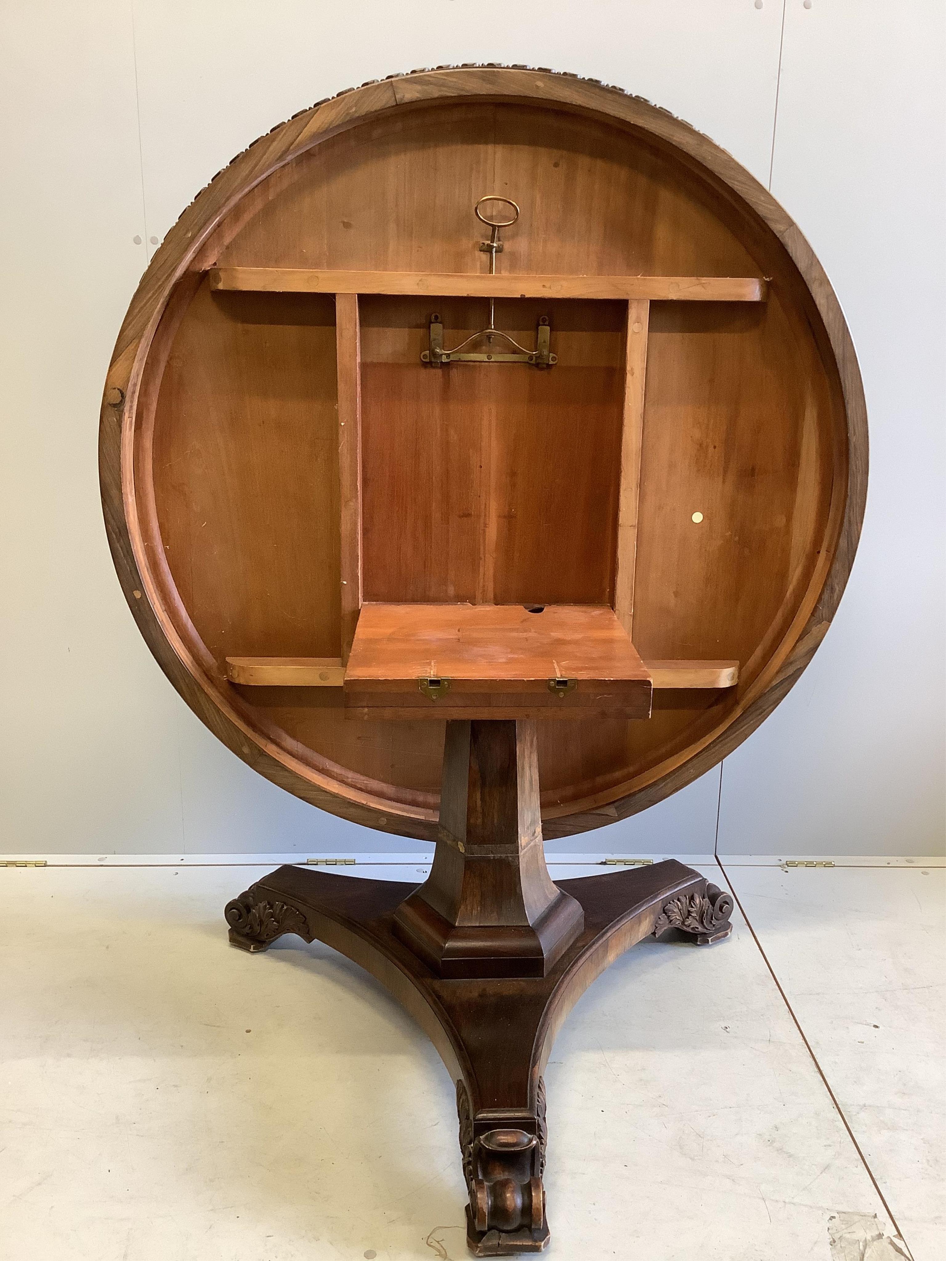 A William IV circular rosewood centre table, the tilt top with lappet carved edge on single tapered hexagonal column, tripartite slab base with scrolled feet, diameter 135cm, height 72cm